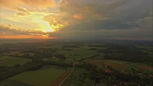 Aerial shot of beautiful green landscape in a sunset with orange clouds. Aerial slow motion.