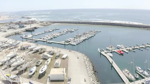 An einem sonnigen Tag neigen sich Drohnenaufnahmen und nähern sich einem Dock voller Boote, was die Kulisse für