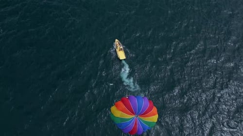 Drone Video of a Colorful Parasail Being Towed By a Speedboat Over the Ocean The Scene Captures the