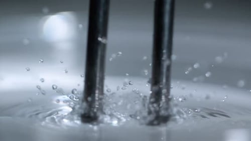 Metallic Rods Splashing Into Water Close Up