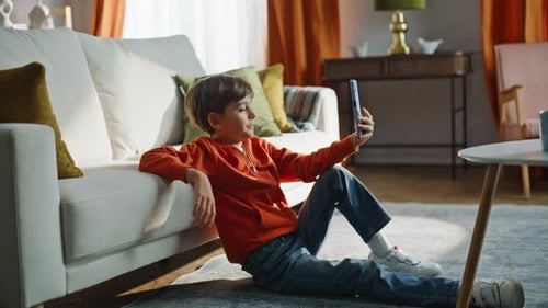 Young Boy Video Calling Leaning on Sofa at Home