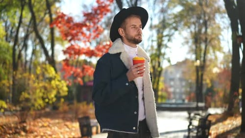 Medium Shot Portrait of Happy Confident LGBT Man Standing in Sunny Autumn Park Drinking Coffee