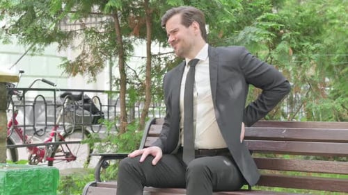 Man on Bench With Back Pain in Urban Park