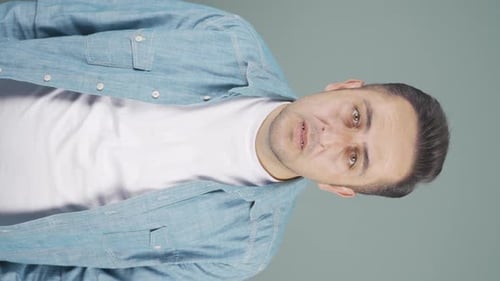 Vertical video of Man looking at camera with curious expression.