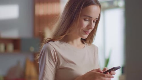 Smiling Woman Using Smartphone in Bright Home