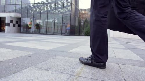 Synergy Collection: A low angle slow motion shot of a businessman walking towards the office buildin