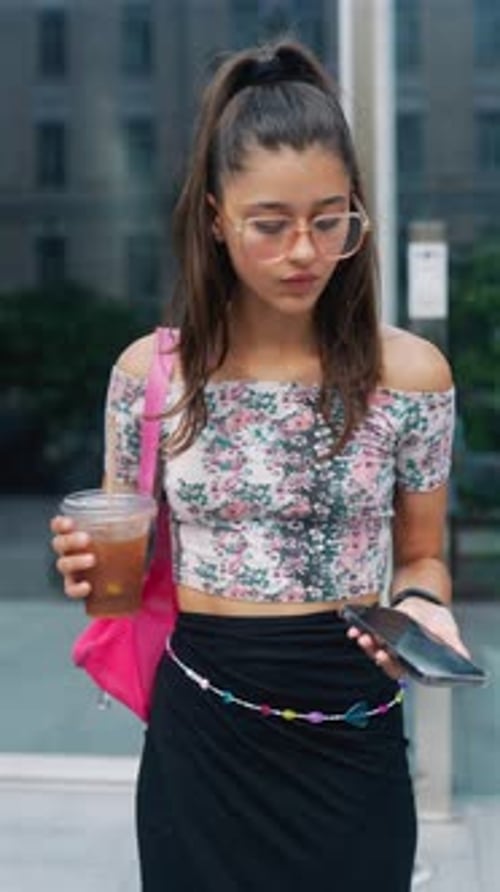 A Gorgeous Young Woman with a Coffee Cup and a Smartphone in Her Hands is Hurrying During Peak Hour