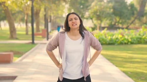 Exhausted Young Woman Resting After Jogging in Park