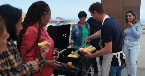 Friends Enjoying Outdoor Barbecue With Grilled Corn
