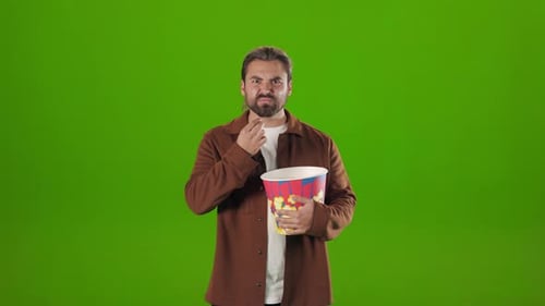Man eating popcorn against a green screen