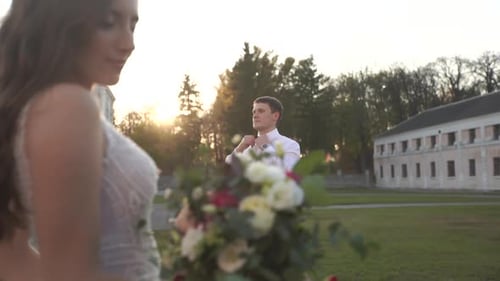 Wedding couple in the park. The groom fixes a butterfly on his neck