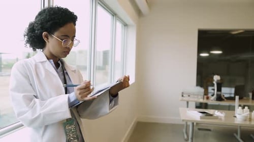 Young Woman Scientist Writing on Clipboard in Lab