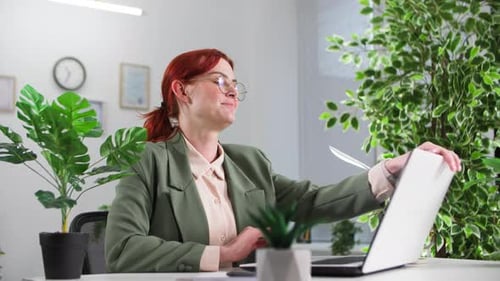 Portrait d'une jeune employée souriante travaillant devant un ordinateur dans un bureau écologique regardant