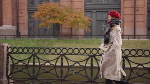 Woman Walks Along the Granite Embankment Along the River on an Autumn Cloudy Day