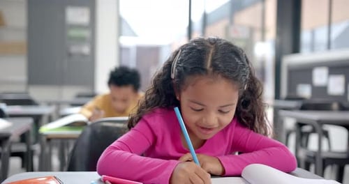In school classroom, biracial girl with curly hair focusing on writing