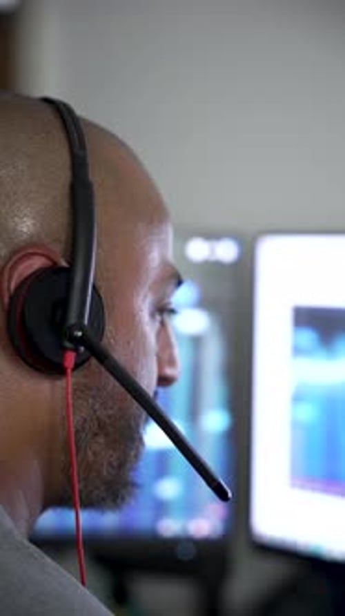 Operador concentrado con auriculares trabajando en el ordenador. Vídeo vertical