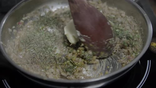 Close-up of a chef mixing ingredients in a metal pan. Preparing a delicious café de paris sauce for