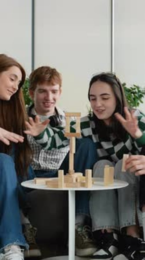 Teenagers Playing Jenga Building Wooden Block Tower Together
