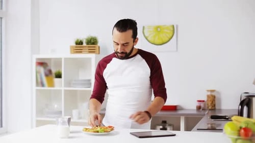 Man Using Tablet, Eating Breakfast in Modern Kitchen