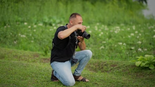 Fotógrafo que captura la belleza de la naturaleza Un ávido fotógrafo se arrodilla en una exuberante pradera, cámara en mano
