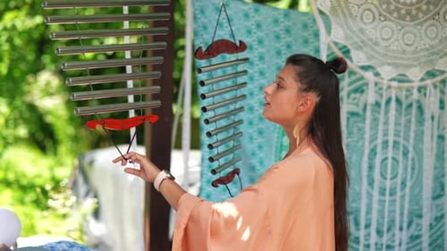 A Young Beautiful Woman Plays a Musical Instrument in the Garden