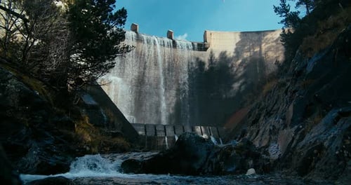 Hydroelectric Dam with Flowing Water Into Mountain River in Middle of Forest