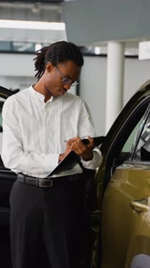 African American Car Dealer Managing Inventory in Showroom
