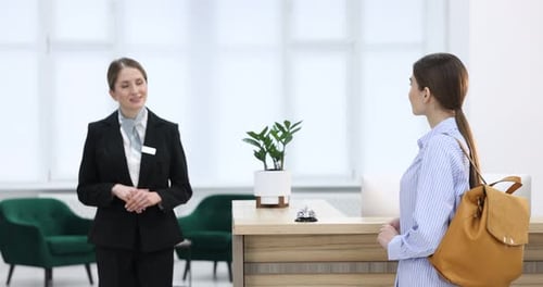 Rezeptionistin arbeitet mit Gästen an der Rezeption im Innenbereich