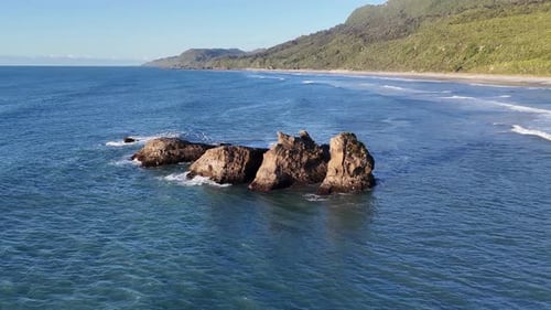Majestic Ocean Waves Surround Rugged Coastal Rock Formation in Serene Aerial View New Zealand