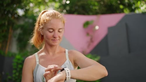 Redhead Female Athlete Checks Smart Watch After Training in Tropical Outdoor Gym She Monitors