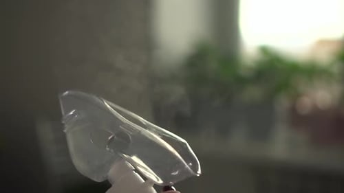 Inhalation Mask Closeup on a Background of Green Flowers Steam is Coming Out of the Mask Slow Motion