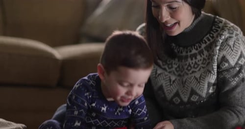 Excited Boy Opens Gift with Smiling Woman