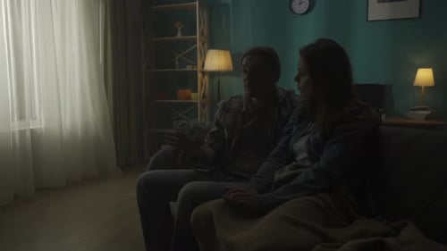 A Couple is Sitting on a Sofa in a Dark Room Close Up A Man Listens to a Woman Holds Her Hand Hugs