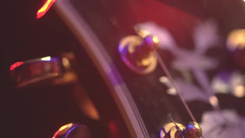 Head of electric guitar with bokeh on stage. Tilt down. Extreme close up