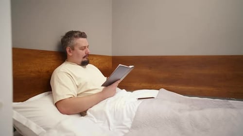 Mature man reading a book in bed before sleeping
