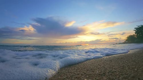 Slow Motion of Ocean Wave on a Sandy Beach at Sunset