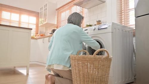 Silver-Haired Woman Putting Laundry Into Washing Machine