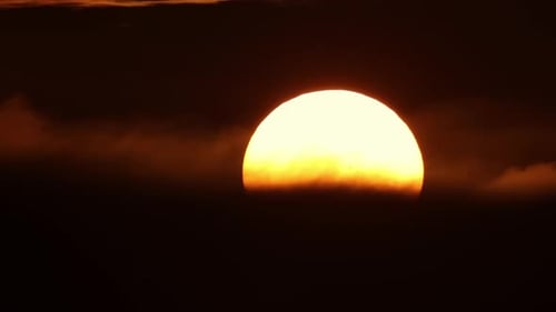 Eine riesige gelbe runde Sonne geht hinter schwarzen Wolken unter