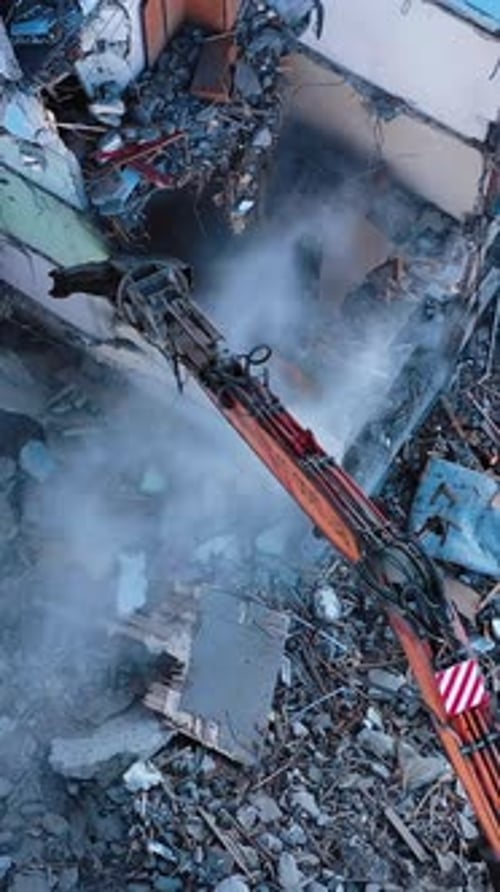 Huge building being demolished with the help of a tractor.