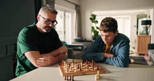 Vater, Junge und spielen zu Hause Schach zur kognitiven Entwicklung, Herausforderung