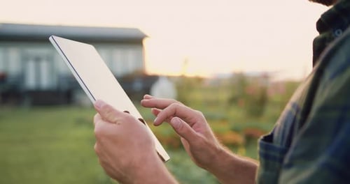 Nahaufnahme der Hände von Landwirten, die sich Notizen machen und nach Informationen auf einem Tablet auf einem landwirtschaftlichen Feld suchen