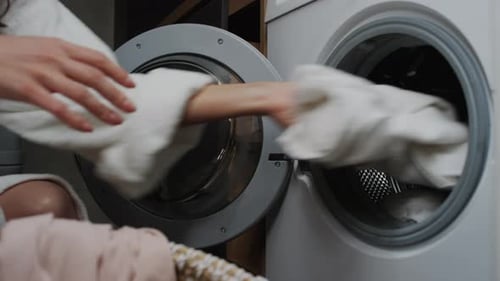 Woman Loading Clothes into Washing Machine in Home