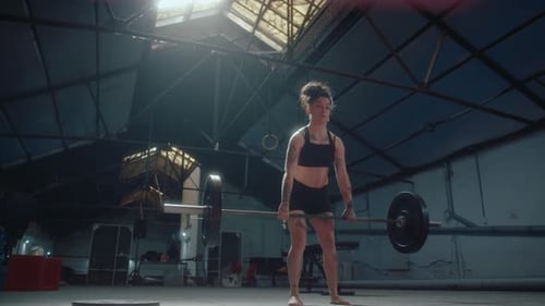 Young Woman Lifting Weighted Barbell in a Gym