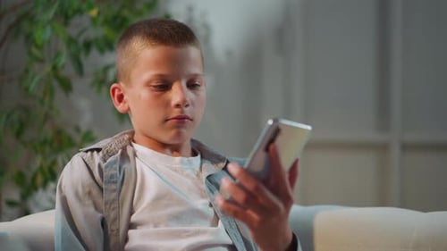 Young Boy Using Smartphone Indoors on Sofa