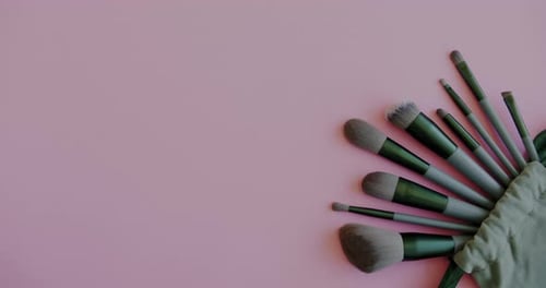 Closeup Top View of Beauty Products Eye Shadow Palette and Makeup Brushes Kit and Female Hand on