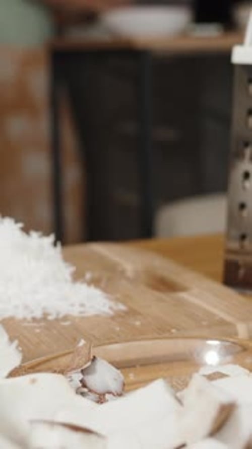Vertical video. A Kitchen Table Covered in Coconut and Crushed White Flesh.