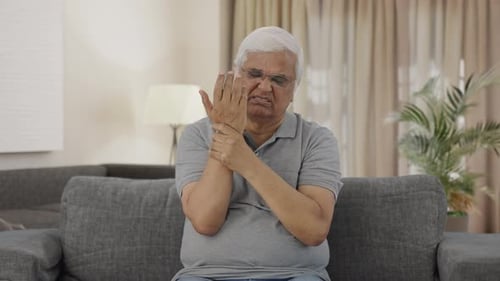Senior Man Rubs Wrist and Elbow in Pain