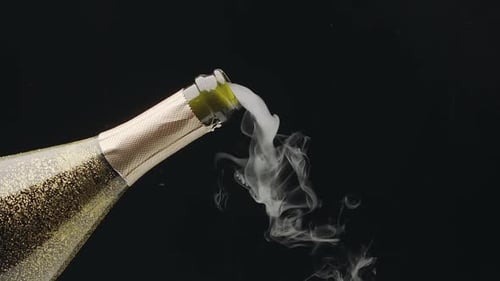 Steam slowly comes out of the neck of an open wine bottle of champagne.
