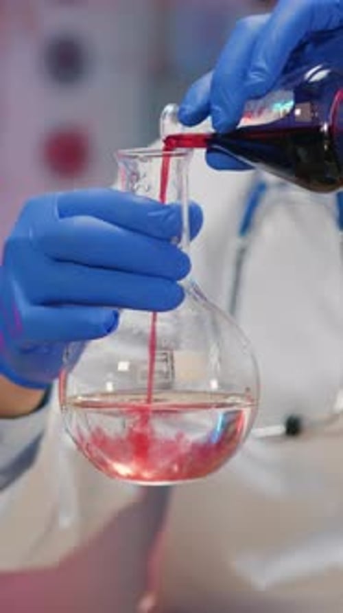 Scientist in Lab Mixing Liquids in Beakers