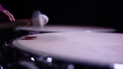 A man playing timpani in a dark room, tilt and small depth of field.